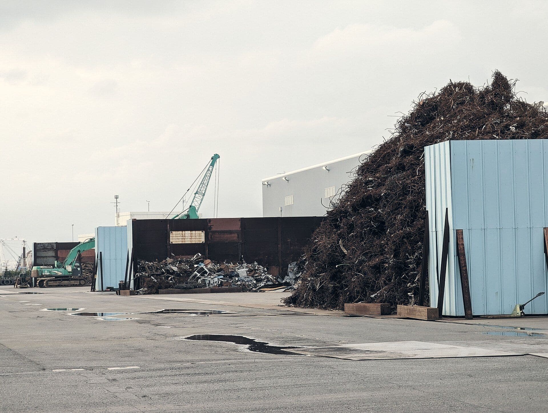 Large heap of rusted scrap next to a warehouse